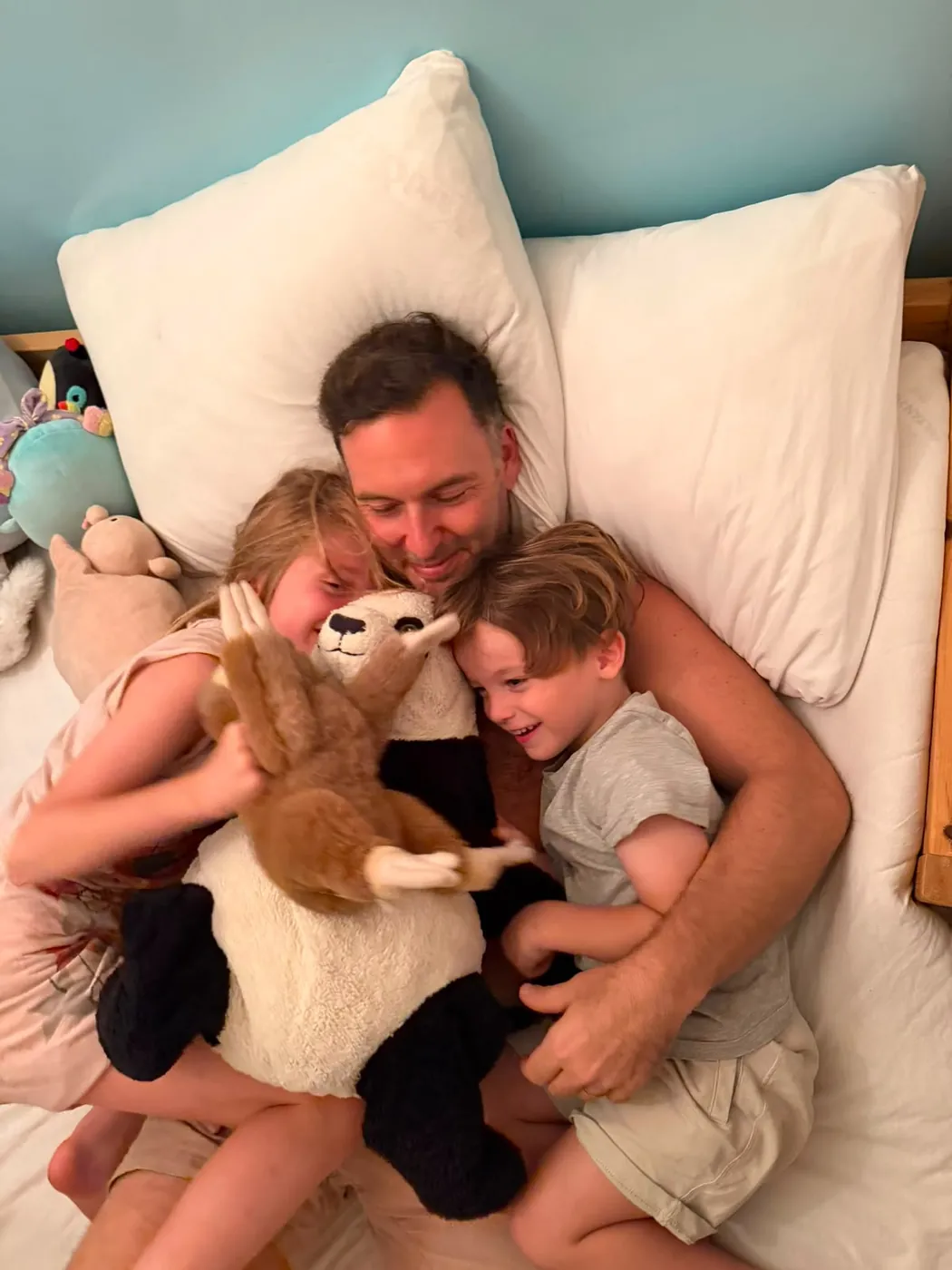 Liran Jakob Rosenfeld cuddling with his two children in bed