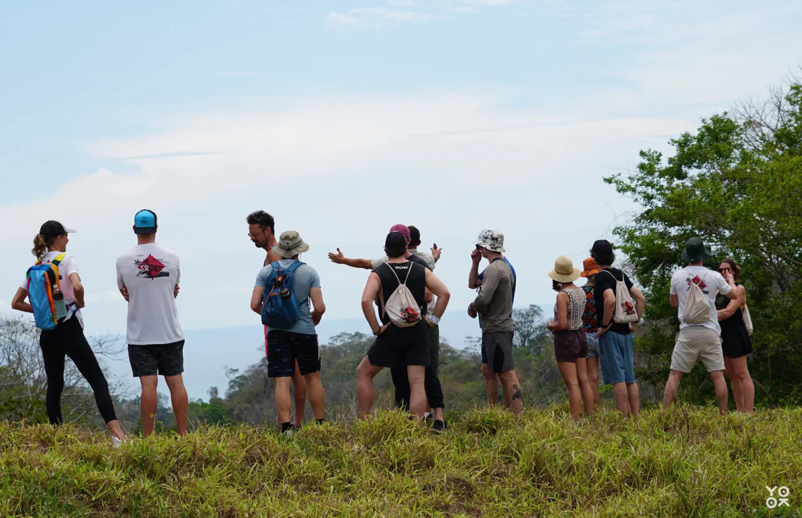 A group of hikers looking out over a valley from a grassy ridgeline
